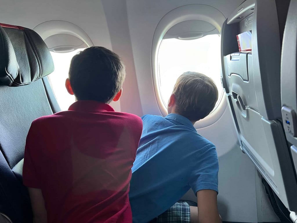 2 boys looking out the airplane window
