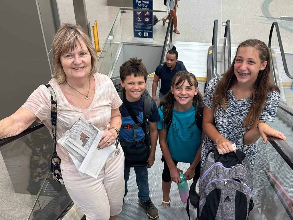3 kids and grandma going up the escalator at the airport