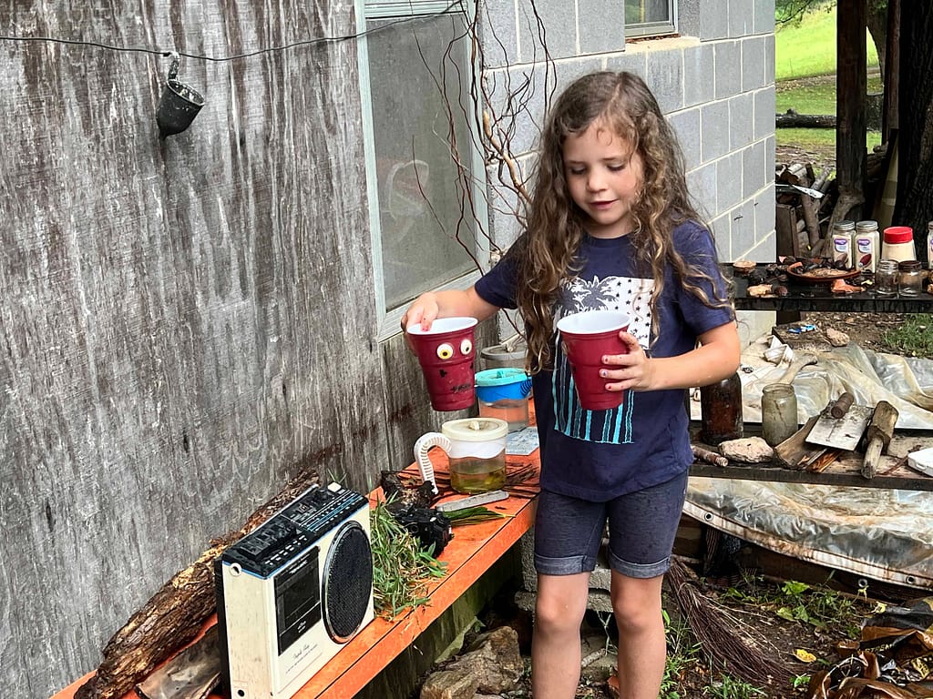 7 year old girl playing in a mud kitchen