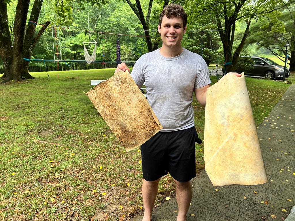 young man holding two pieces of tarp material
