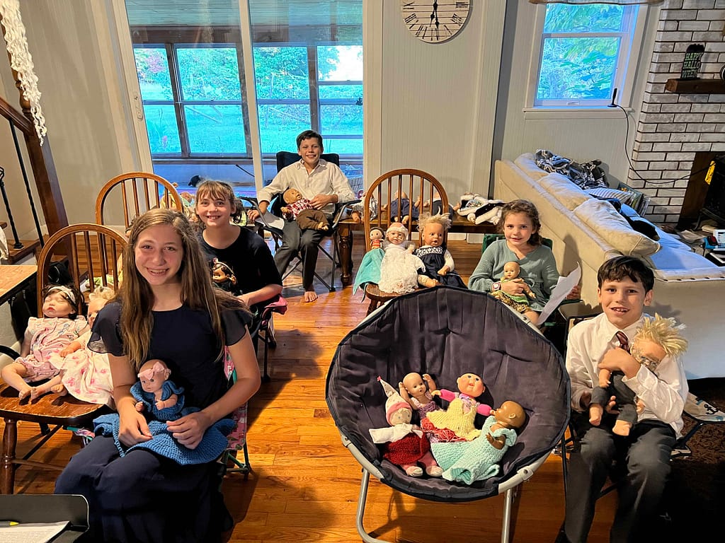 kids sitting in chairs with dolls