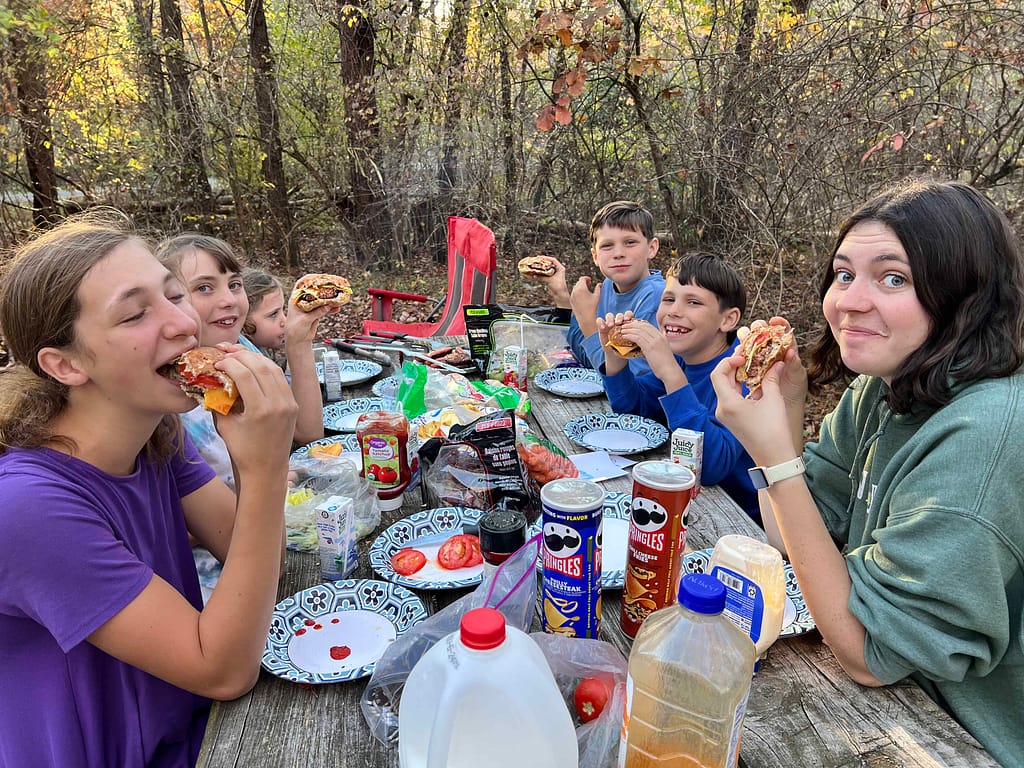 siblings eating hamburgers at a campground