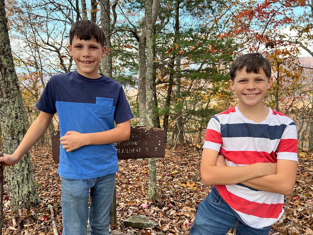 two boys standing by a hiking sign