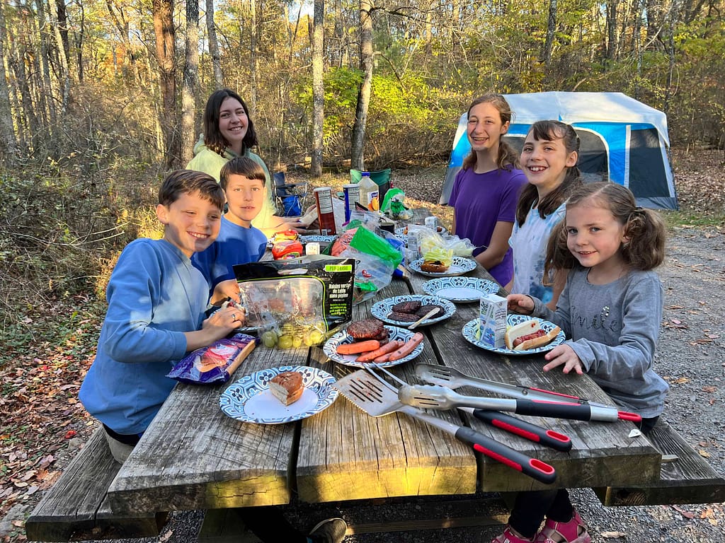 siblings eating hamburgers at a campground