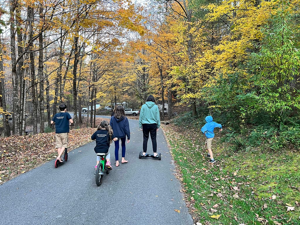 6 kids riding around a campground in fall