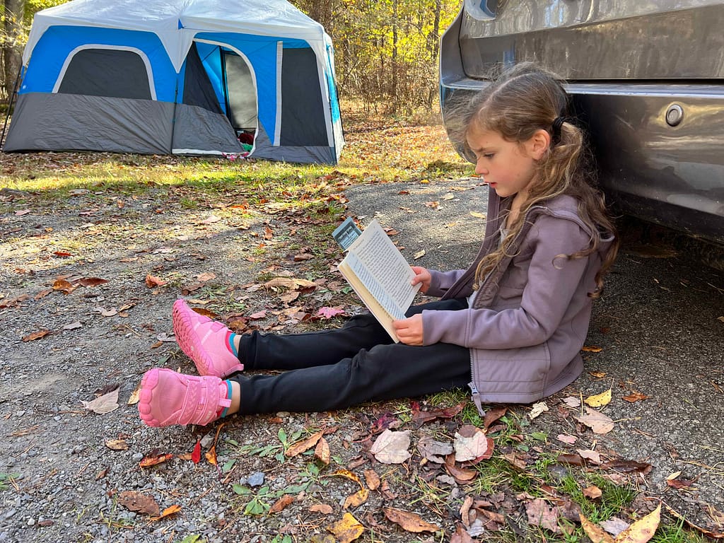 7 year old girl reading at a campground