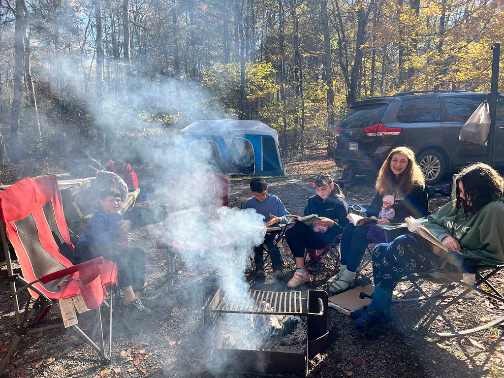Kids reading around the campfire in the morning