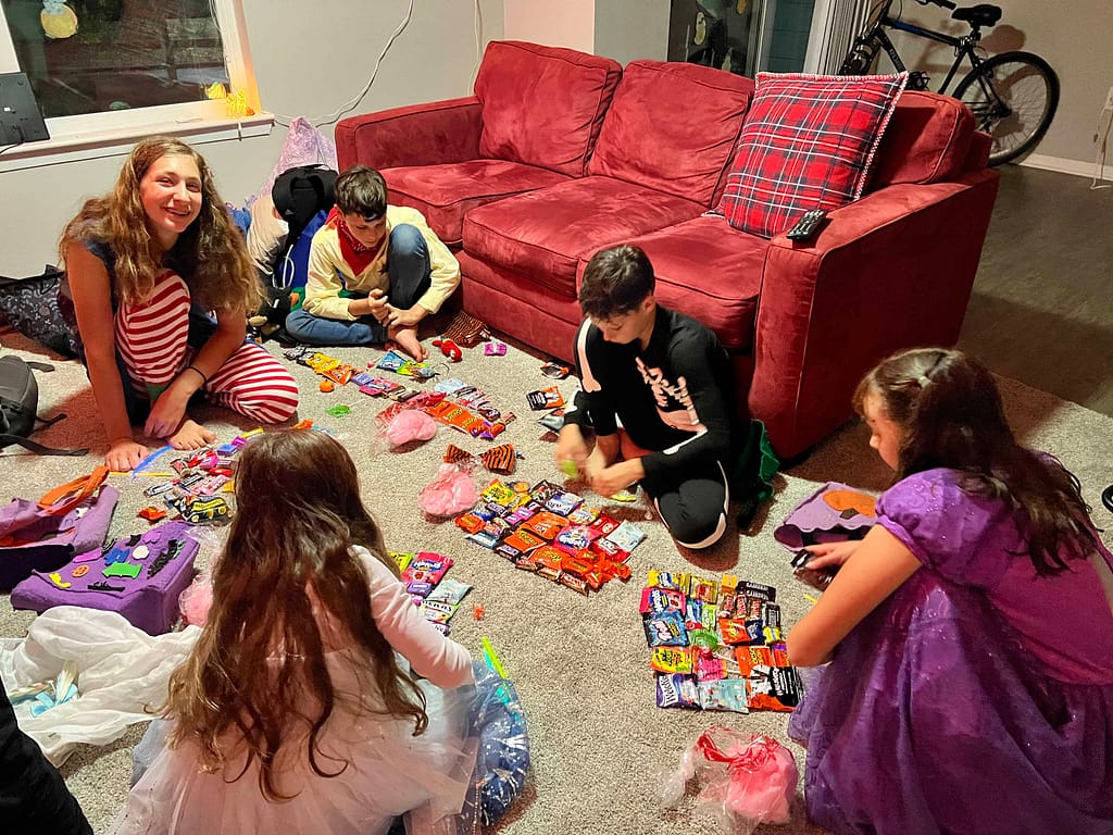 5 kids sorting through their Halloween candy on the living room floor