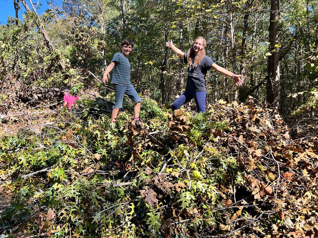 2 kids jumping on a pile of branches