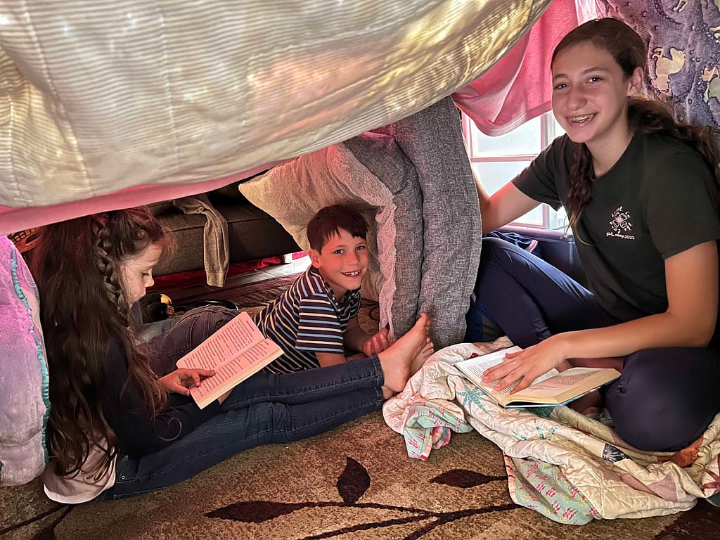 kids reading in a blanket fort