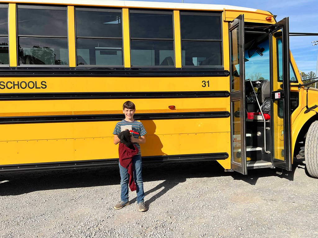 9 year old in front of a school bus