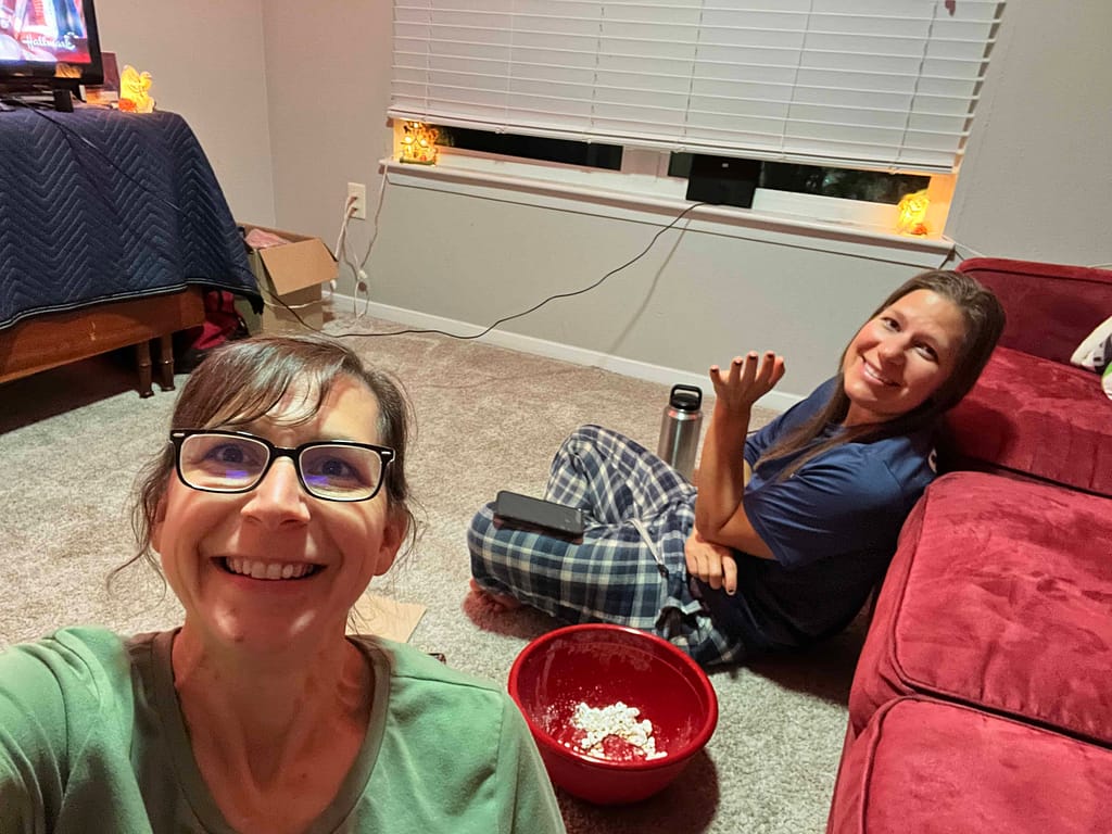 two adult sisters eating popcorn together