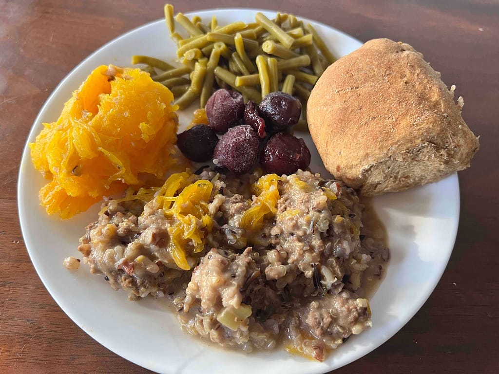 a dinner plate with "dinner in a pumpkin" green beans, rolls and cherries