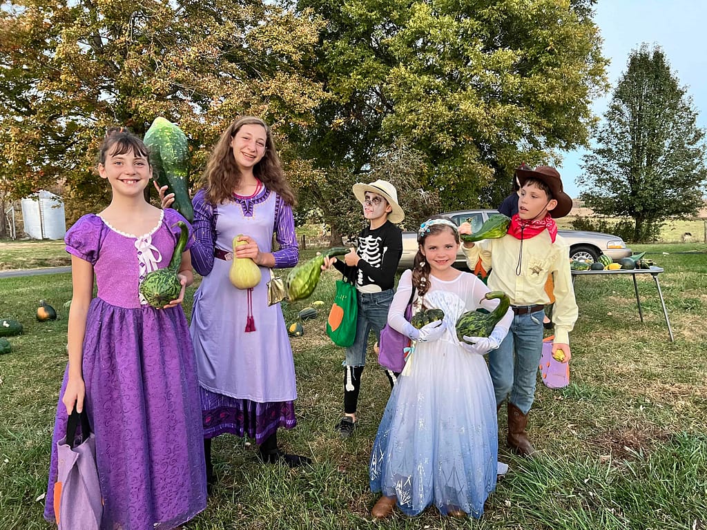 kids holding gourds and dressed up for Halloween