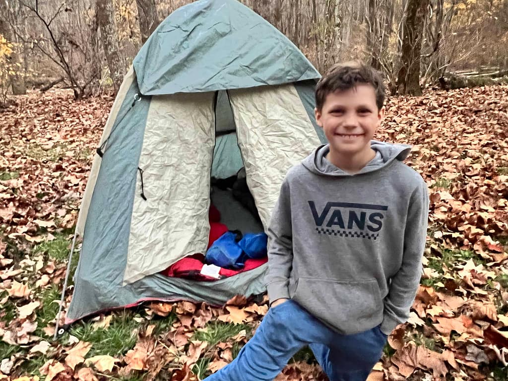 11 year old boy in front of a tent camping