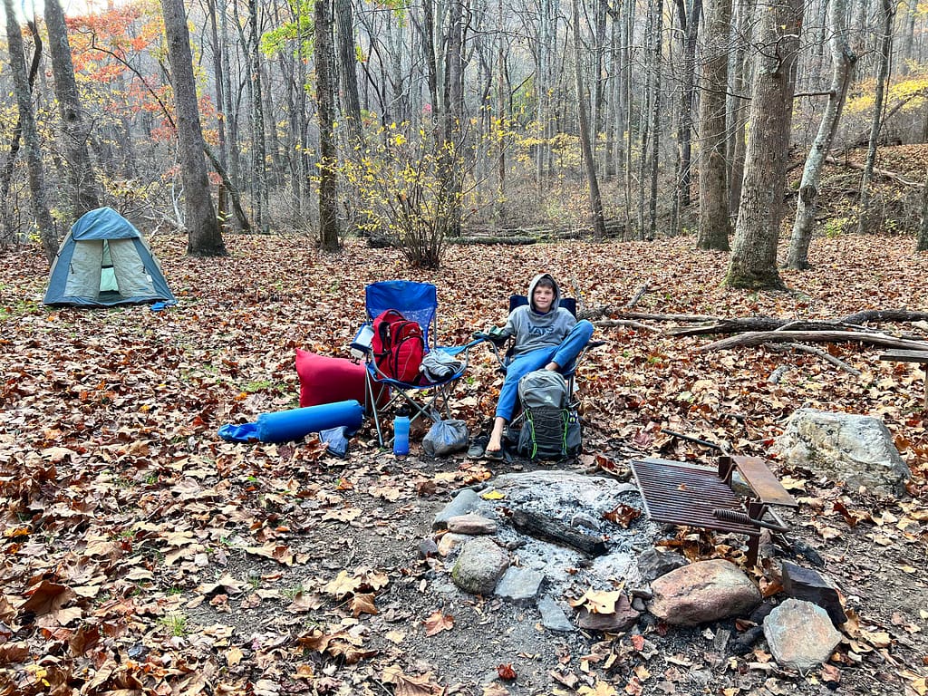 boy sitting in camp chair at campground in late fall