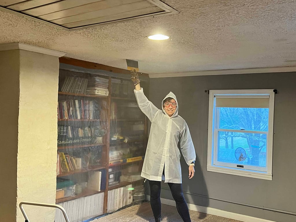 woman in poncho scraping popcorn ceiling