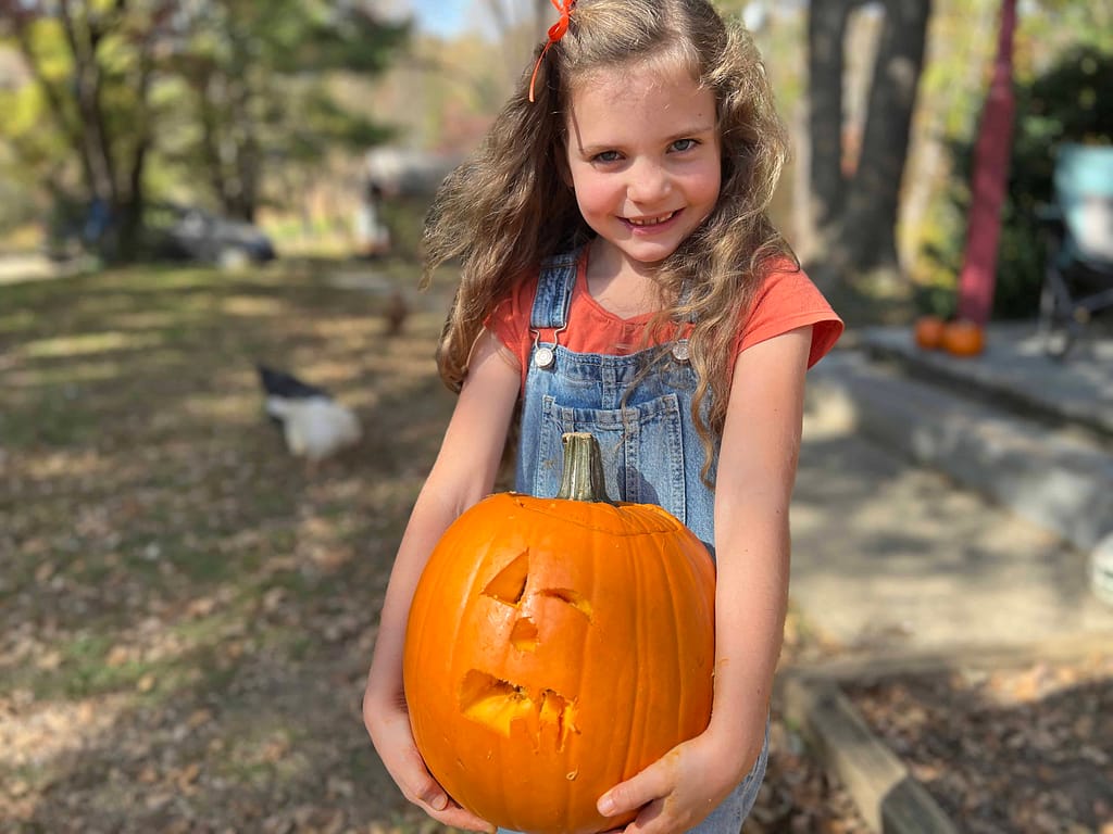 7 year old girl holding carved pumpkin
