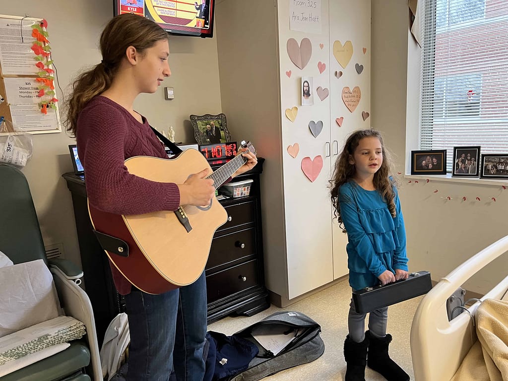 a teen girl playing her guitar at the hospital