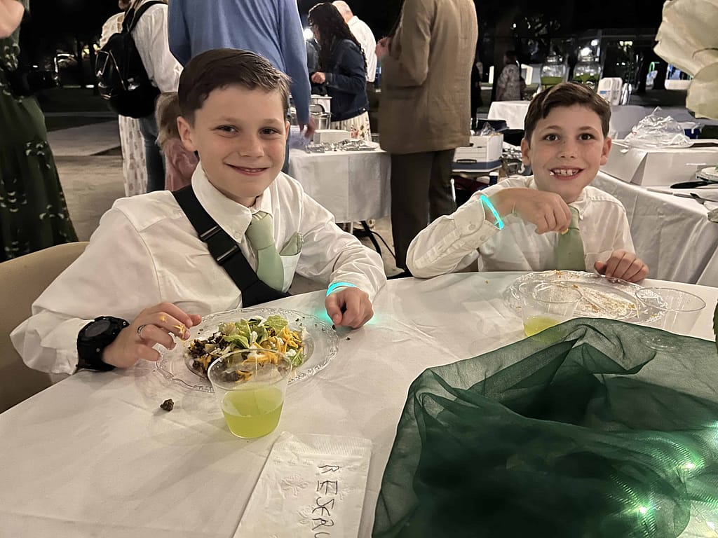 two young brothers eating at a wedding reception