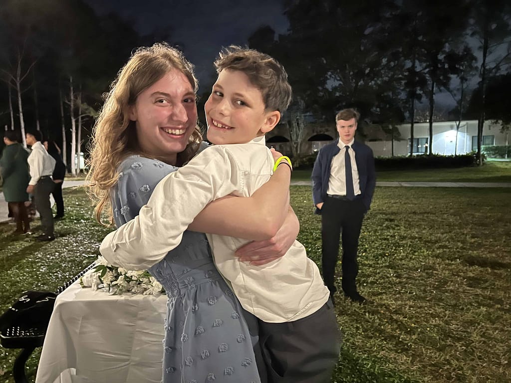 college sister and younger brother hugging