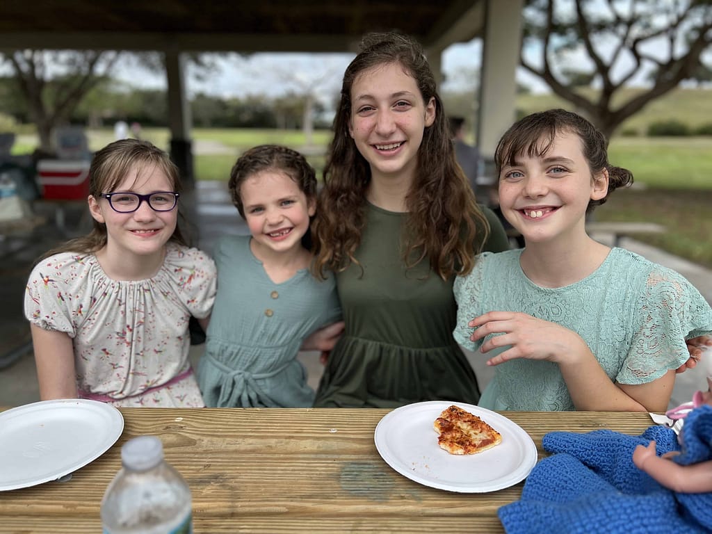4 girls eating pizza at the park