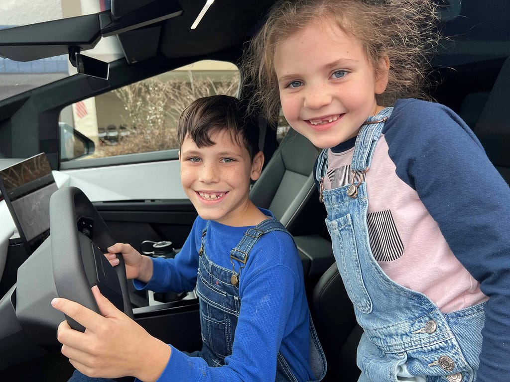 two kids sitting in a Tesla cybertruck