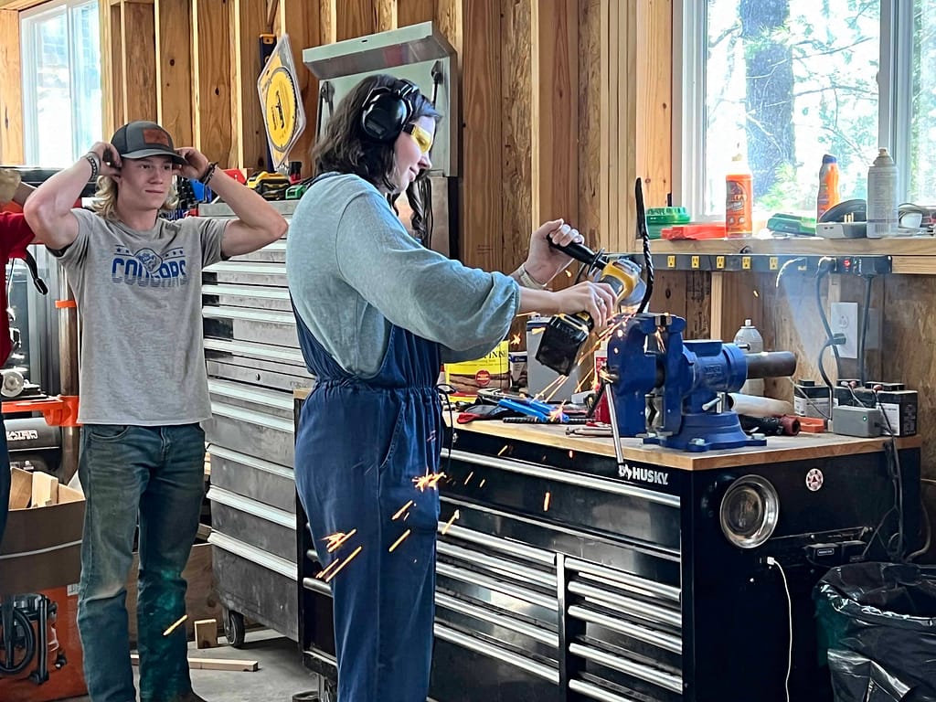 young woman cutting iron in a forge shop