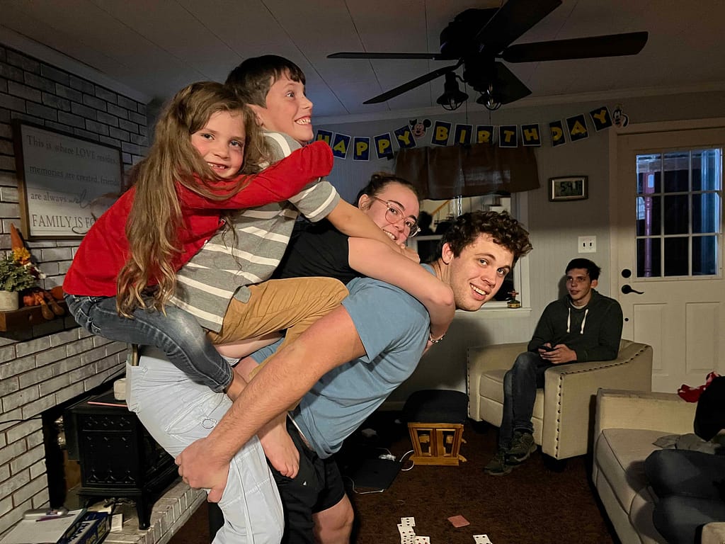young man holding 3 siblings on his back