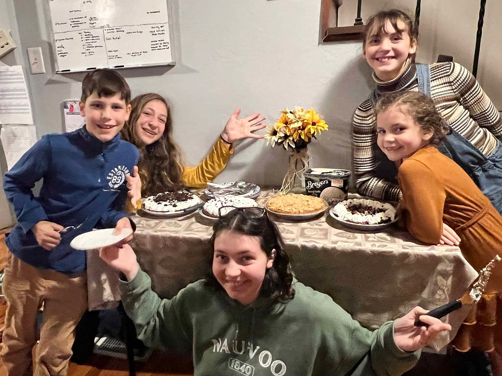 kids displaying the Thanksgiving pie table