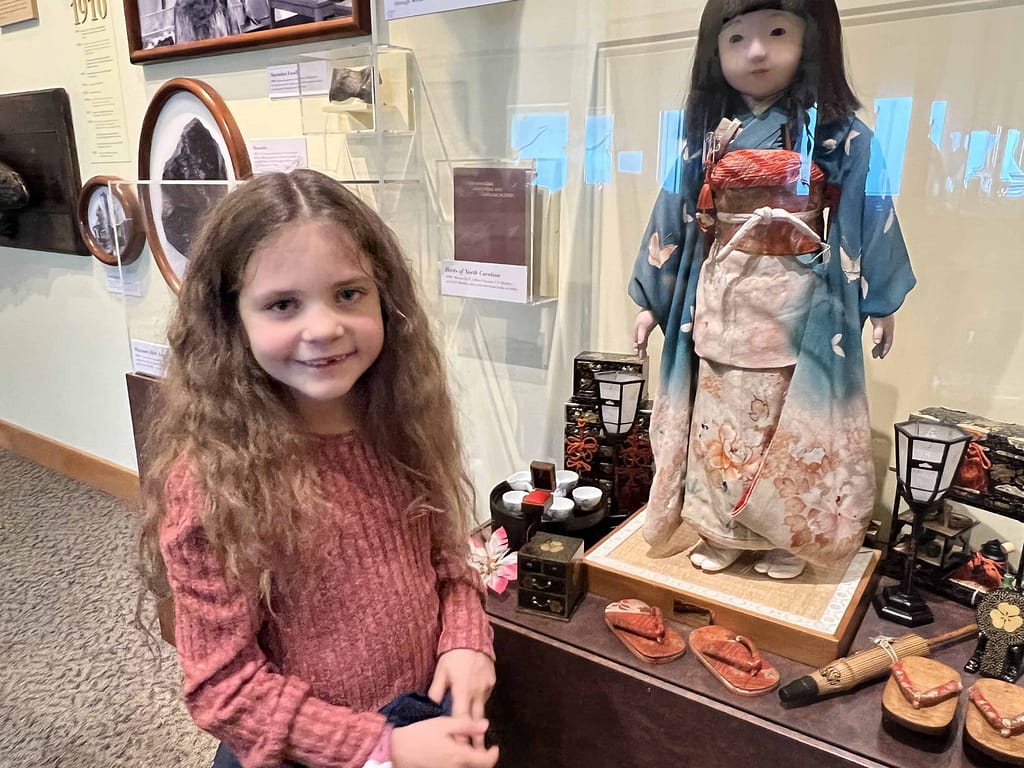 girl looking at a doll at a museum