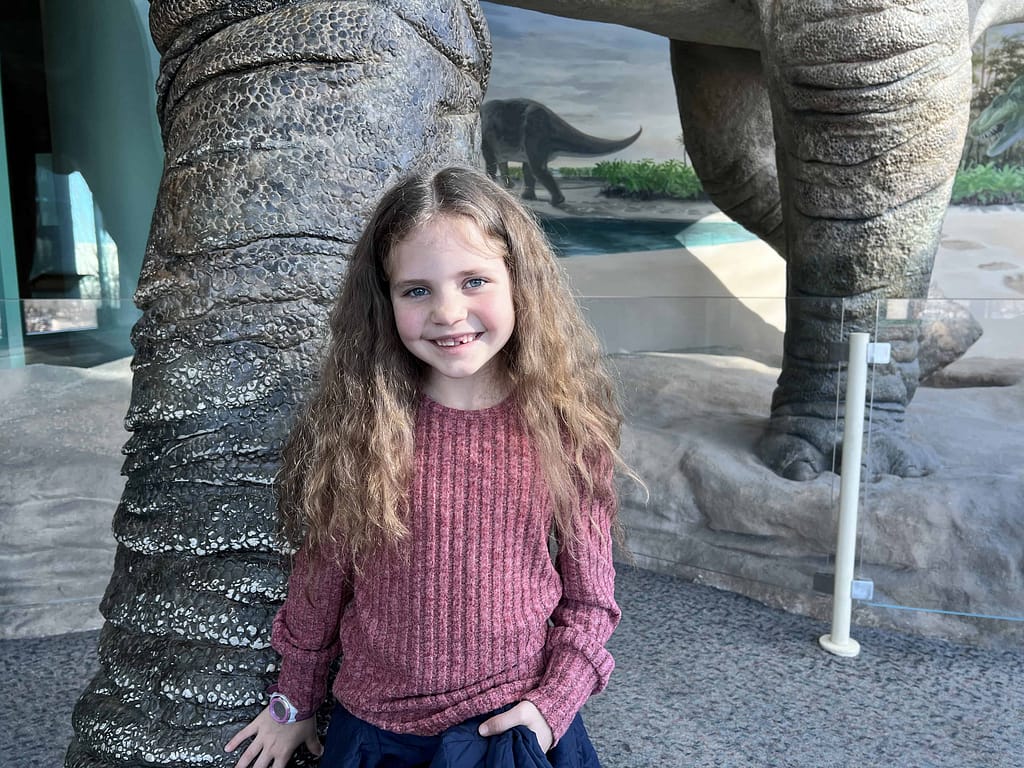 girl by dinosaur at museum