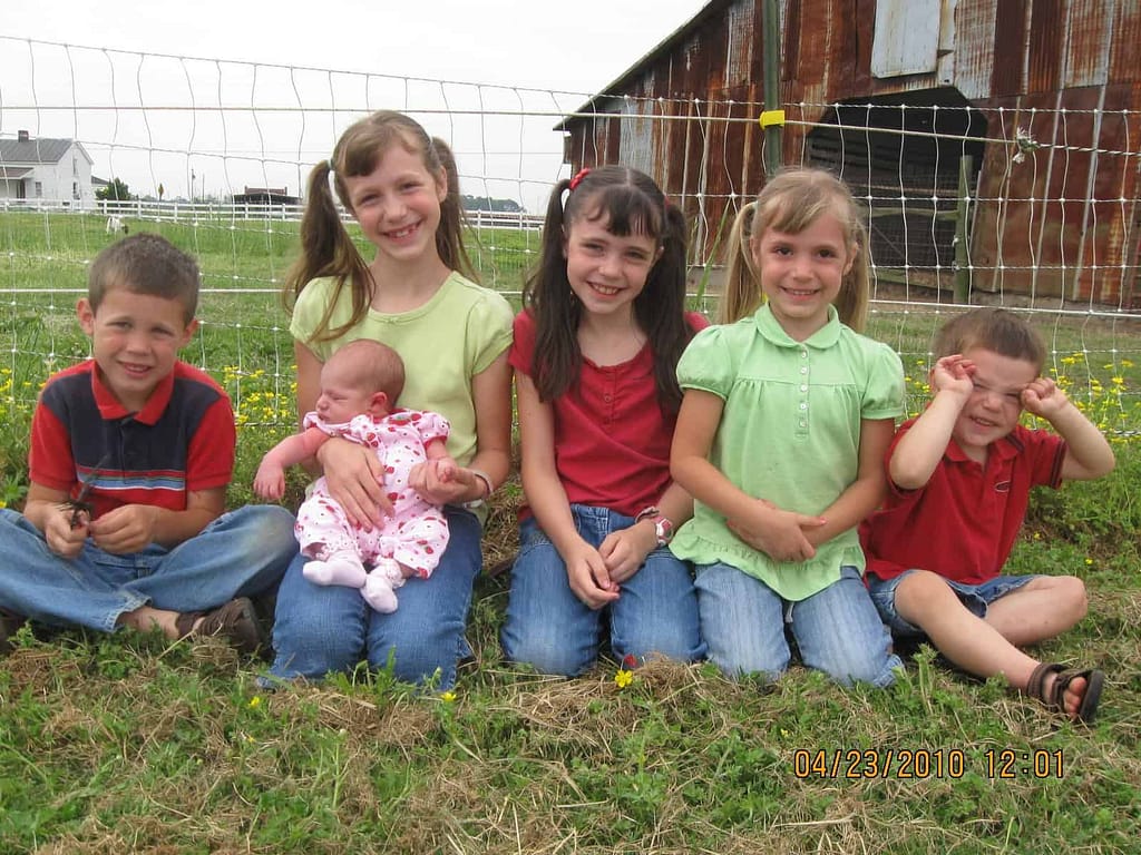 6 little kids wearing green and red at a strawberry patch