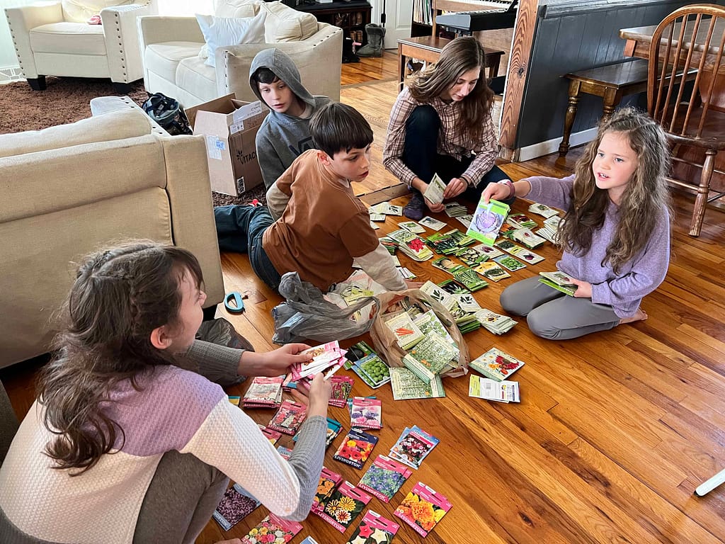 5 kids looking through piles of seed packets on the floor