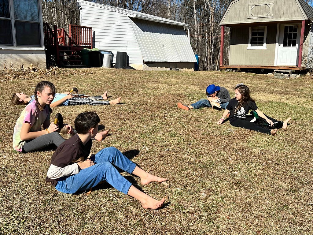 siblings playing with ducks in yard in winter