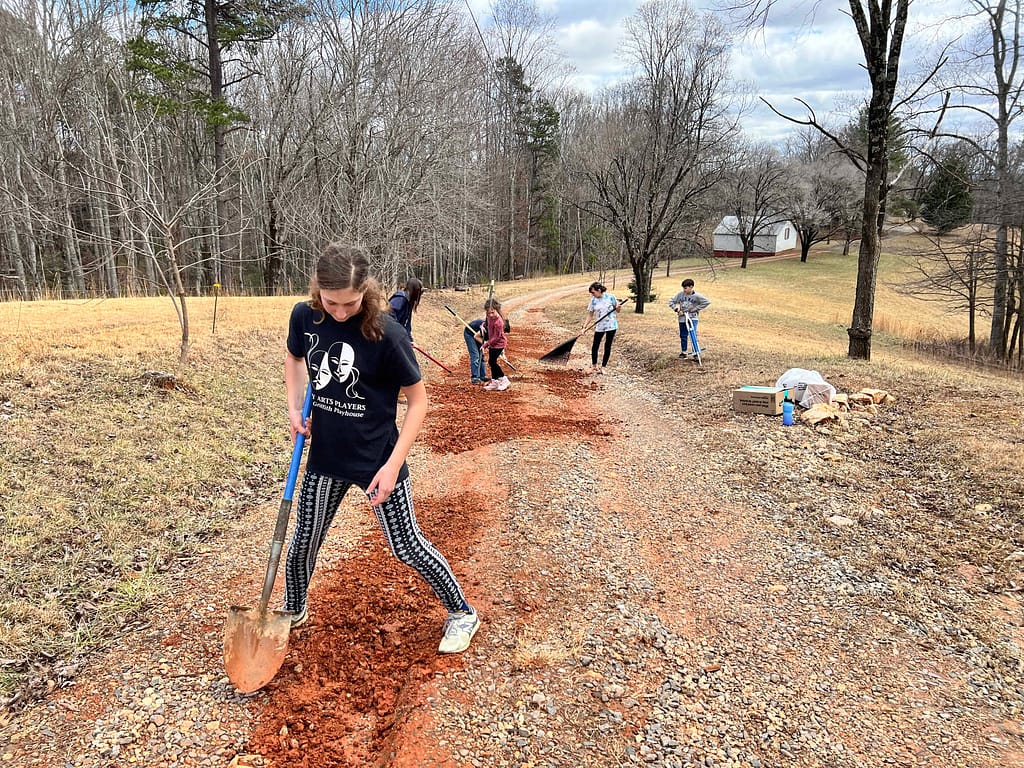 kids smoothing a gravel driveway
