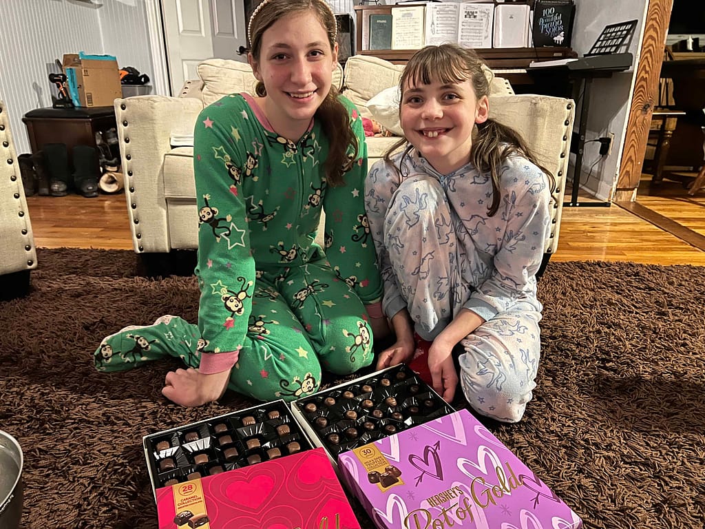 two teen sisters in sleepers eating Valentine chocolates