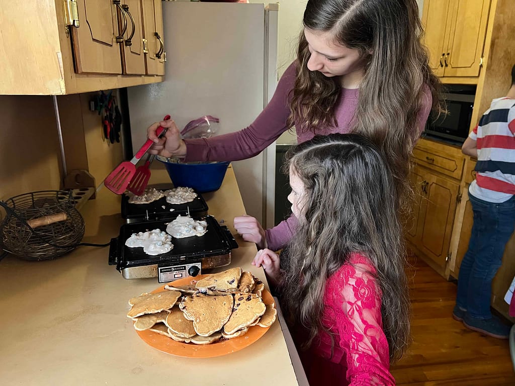 two sisters making heart shaped pancakes