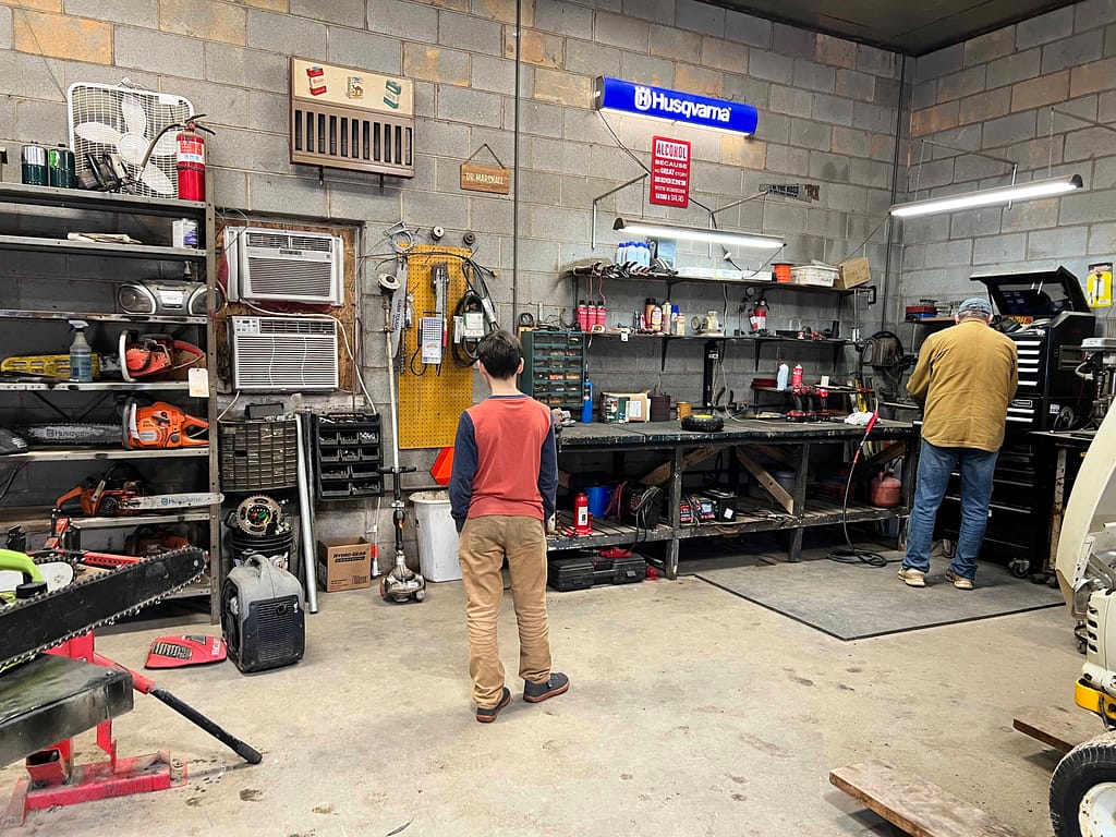 boy in lawnmower guy's workshop