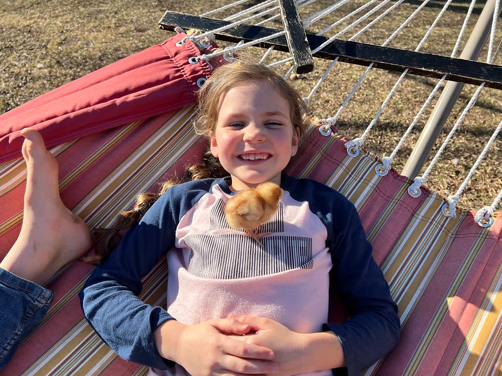 girl holding chick on her chest on a hammock