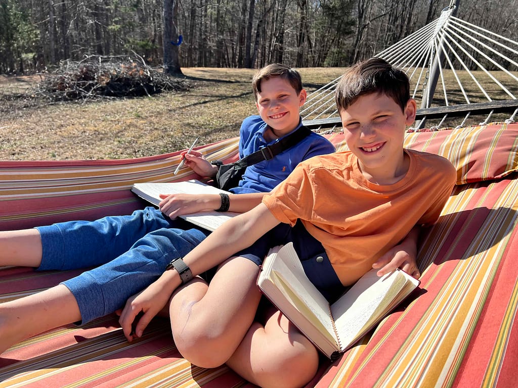 two brothers writing in their journals on a hammock