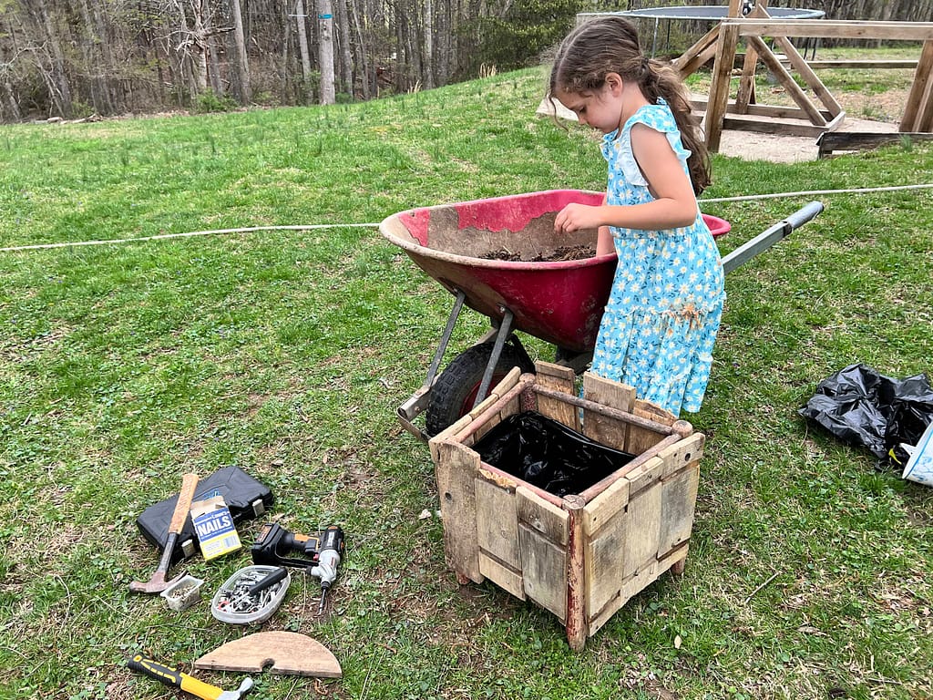 girl adding soil to a wooden planter