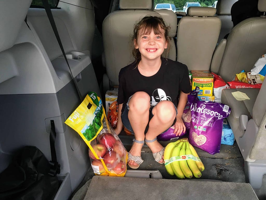girl in back of van with groceries