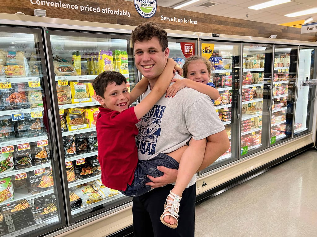 older teen brother holding little brother on the front and little sister on his back