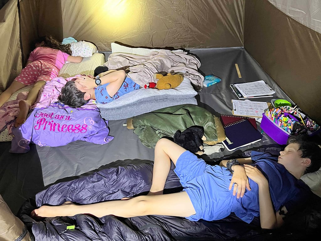 3 kids sleeping in a tent