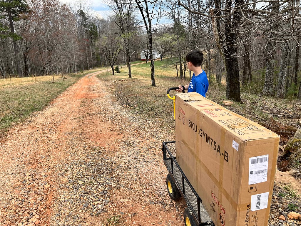 pulling a large package in a wagon down a dirt driveway