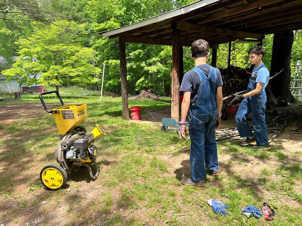 2 boys use a wood chipper