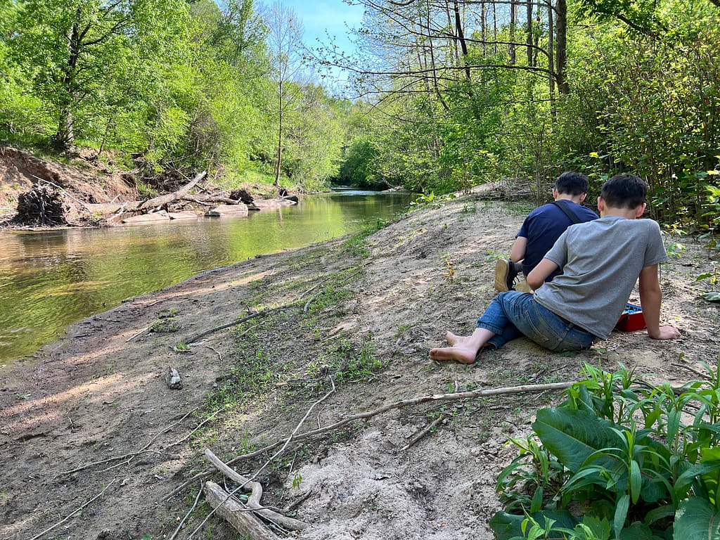 2 boys playing in the sand by the river