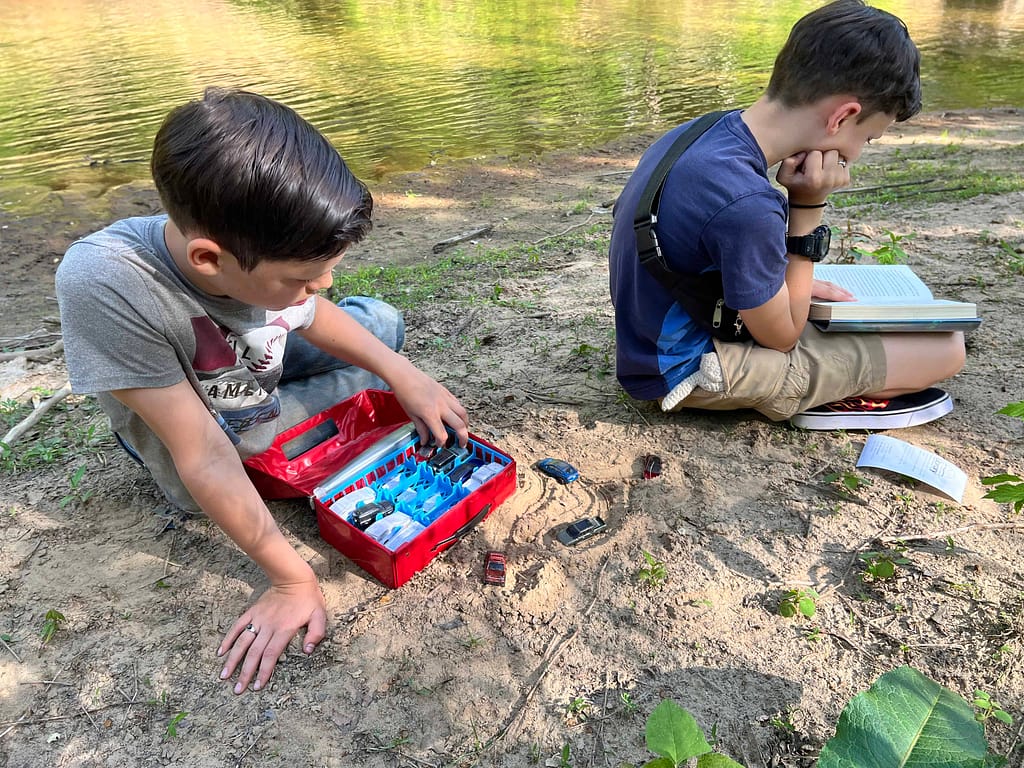 2 boys playing in the sand by the river