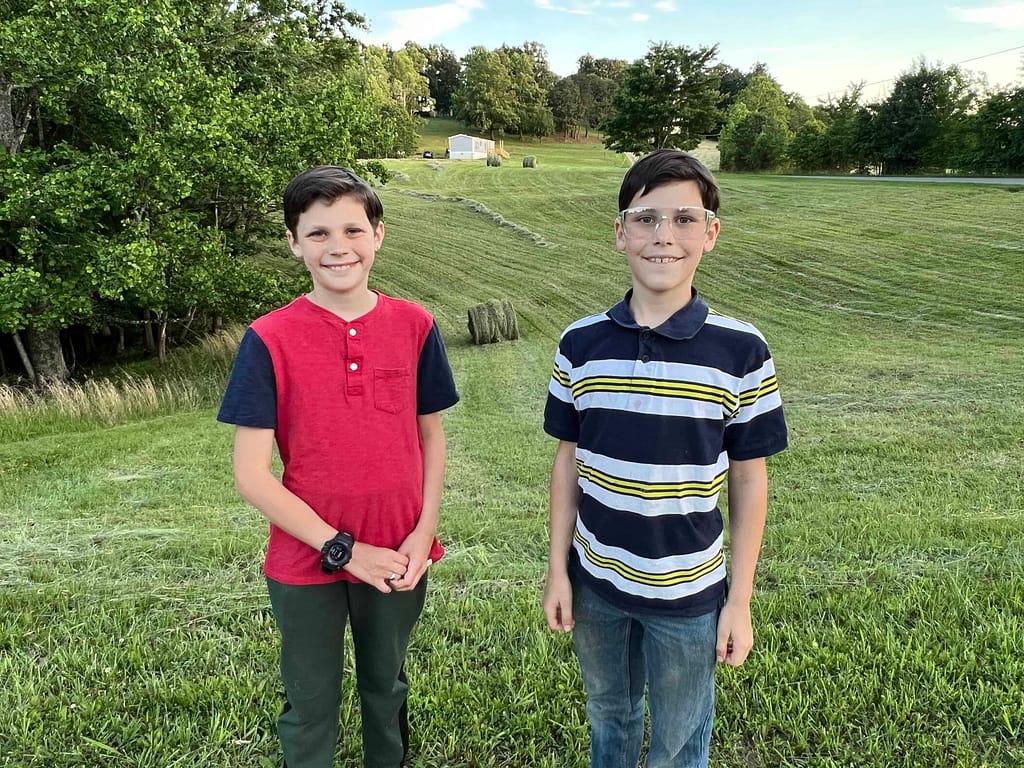 two brothers standing by a field just mowed